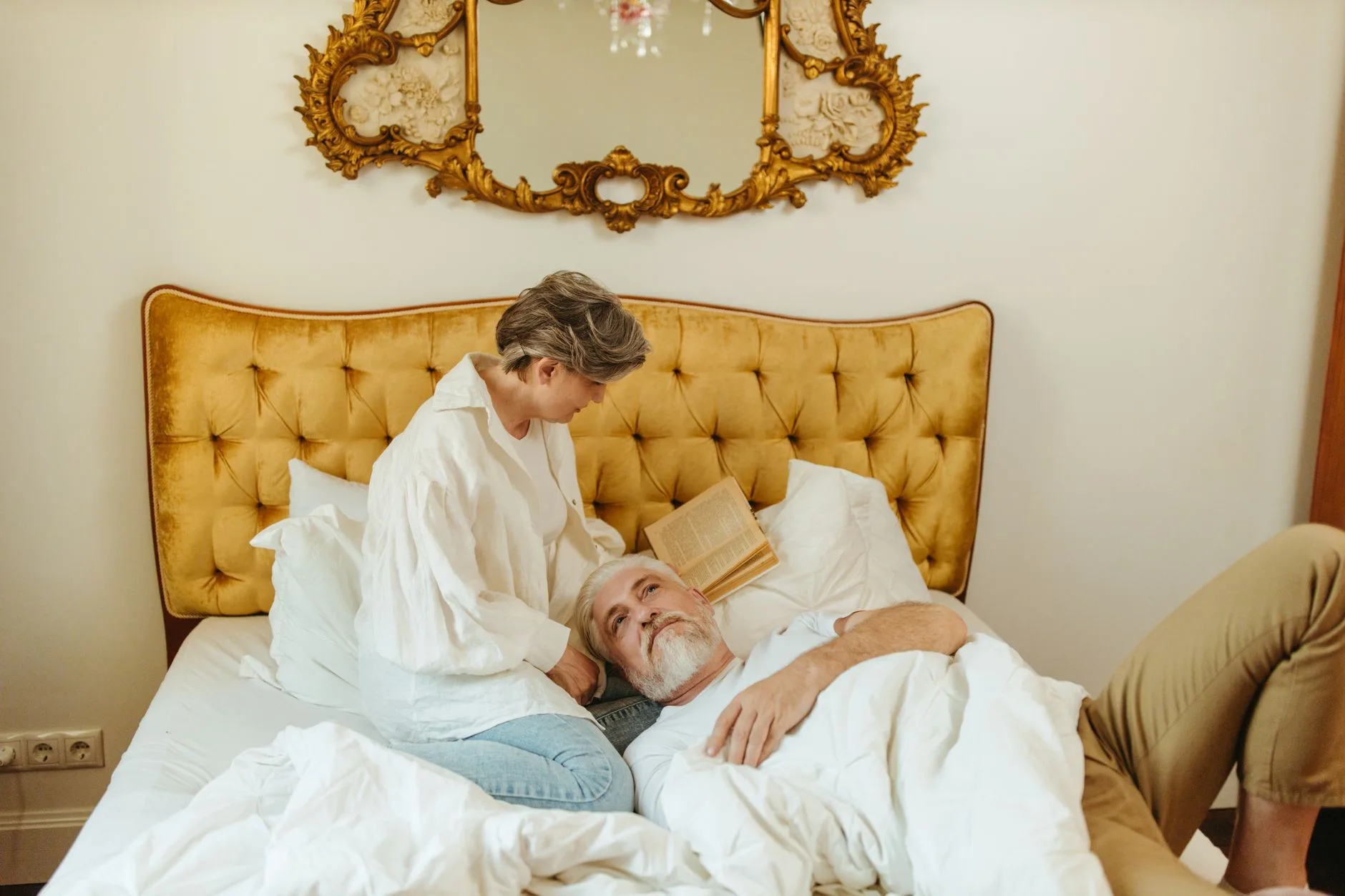 Elderly couple relaxing on bed, woman reading, intimate and peaceful setting.